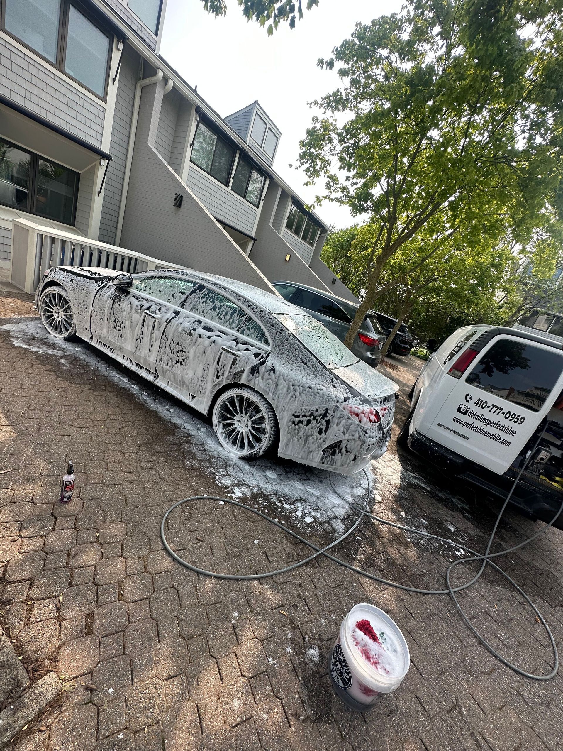 A car is covered in foam in front of a building.