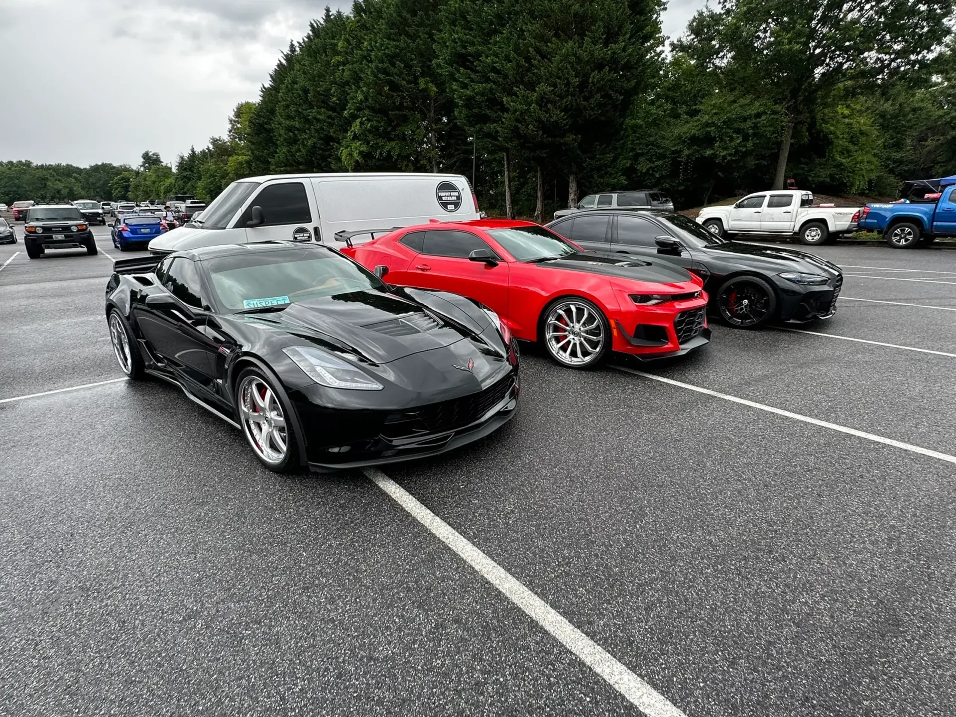 A black car is parked on a sidewalk next to a white van.