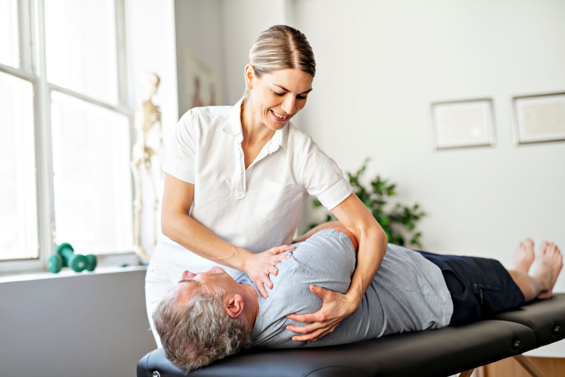 Therapist Adjusting a Man’s Shoulder on a Treatment Table — Back Care Gold Coast In Southport, QLD