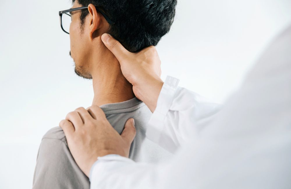 A Man is Getting His Neck Examined by a Doctor — Back Care Gold Coast In Nerang, QLD