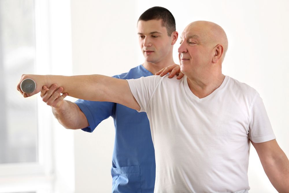 Physical Therapist Guiding a Man’s Arm Stretch — Back Care Gold Coast In Gold Coast, QLD