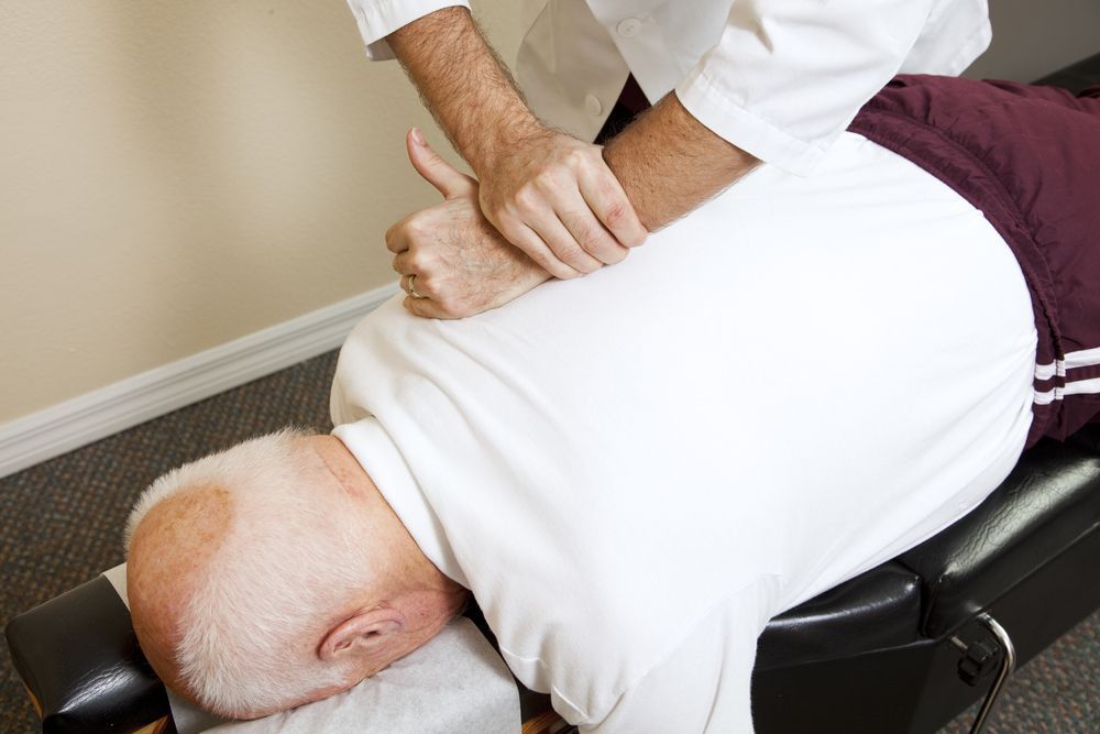 Chiropractor Adjusting a Patient Lying Face Down on a Treatment Table — Back Care Gold Coast In Molendinar, QLD