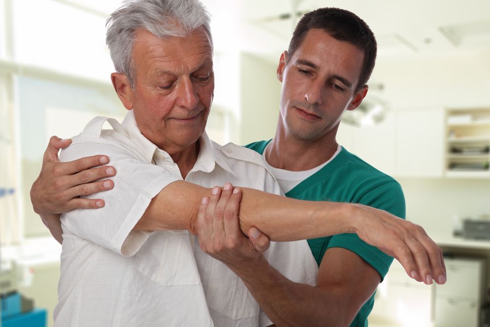 An Elderly Man is Being Helped by a Nurse to Stretch His Arm — Back Care Gold Coast In Nerang, QLD