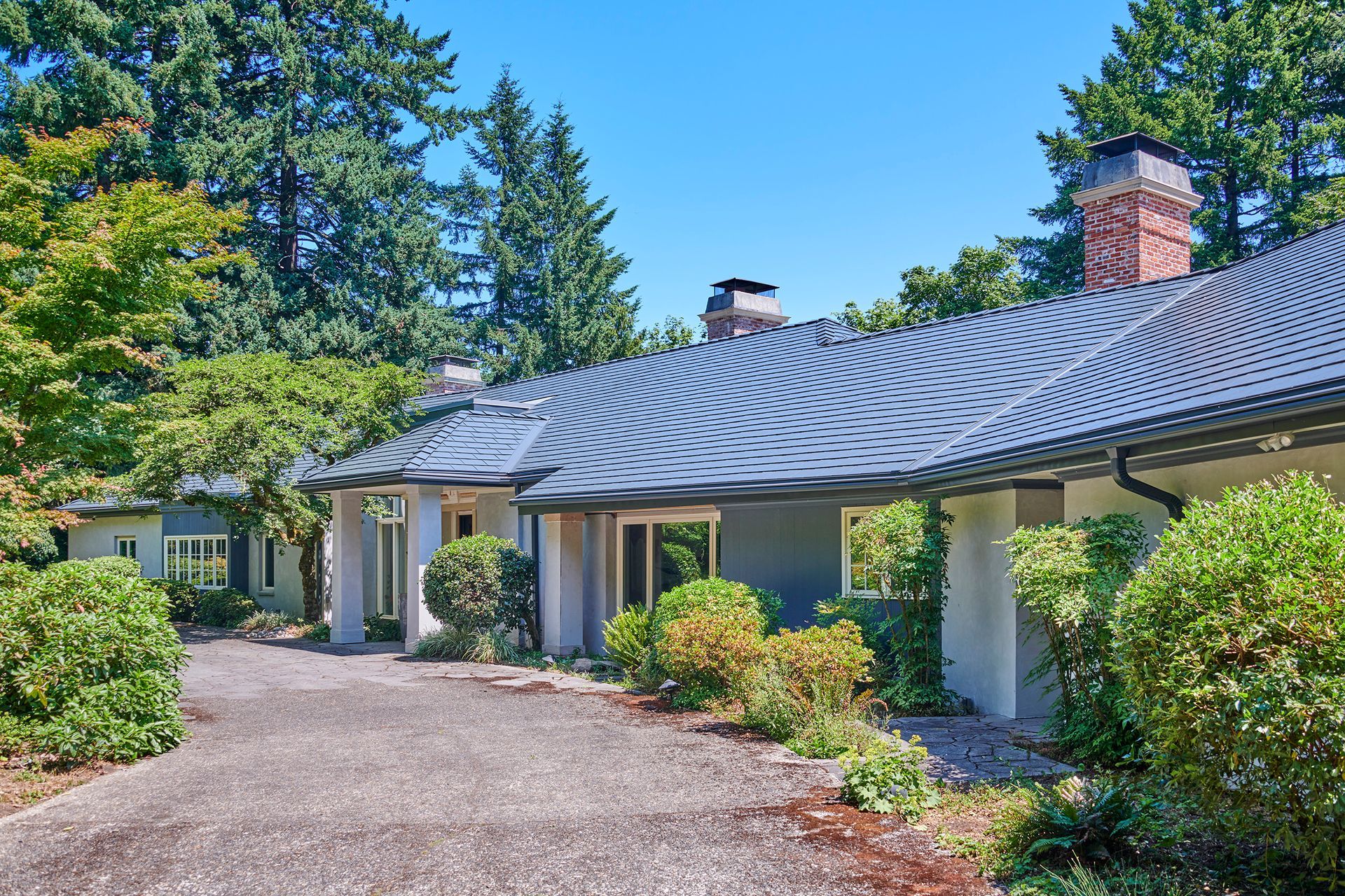 Street-side entryway view of a stylish home in Portland’s Dunthorpe neighborhood with a deep charcoal Interlock aluminum slate roof. Architectural elegance meets long-term metal roofing protection with energy-efficient performance.