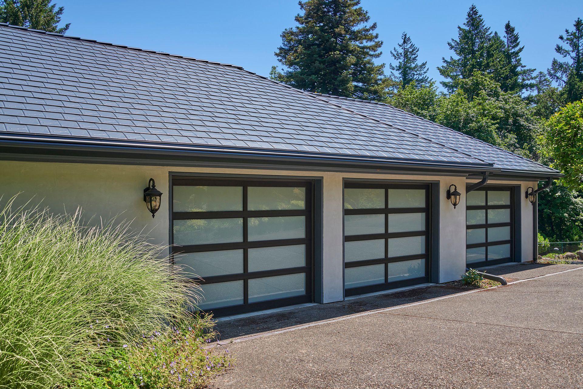 Close-up view of the Interlock aluminum slate roofing system in deep charcoal over a modern three-car garage in Dunthorpe, Portland OR. The slate-style profile enhances home value while offering superior storm and fire resistance.