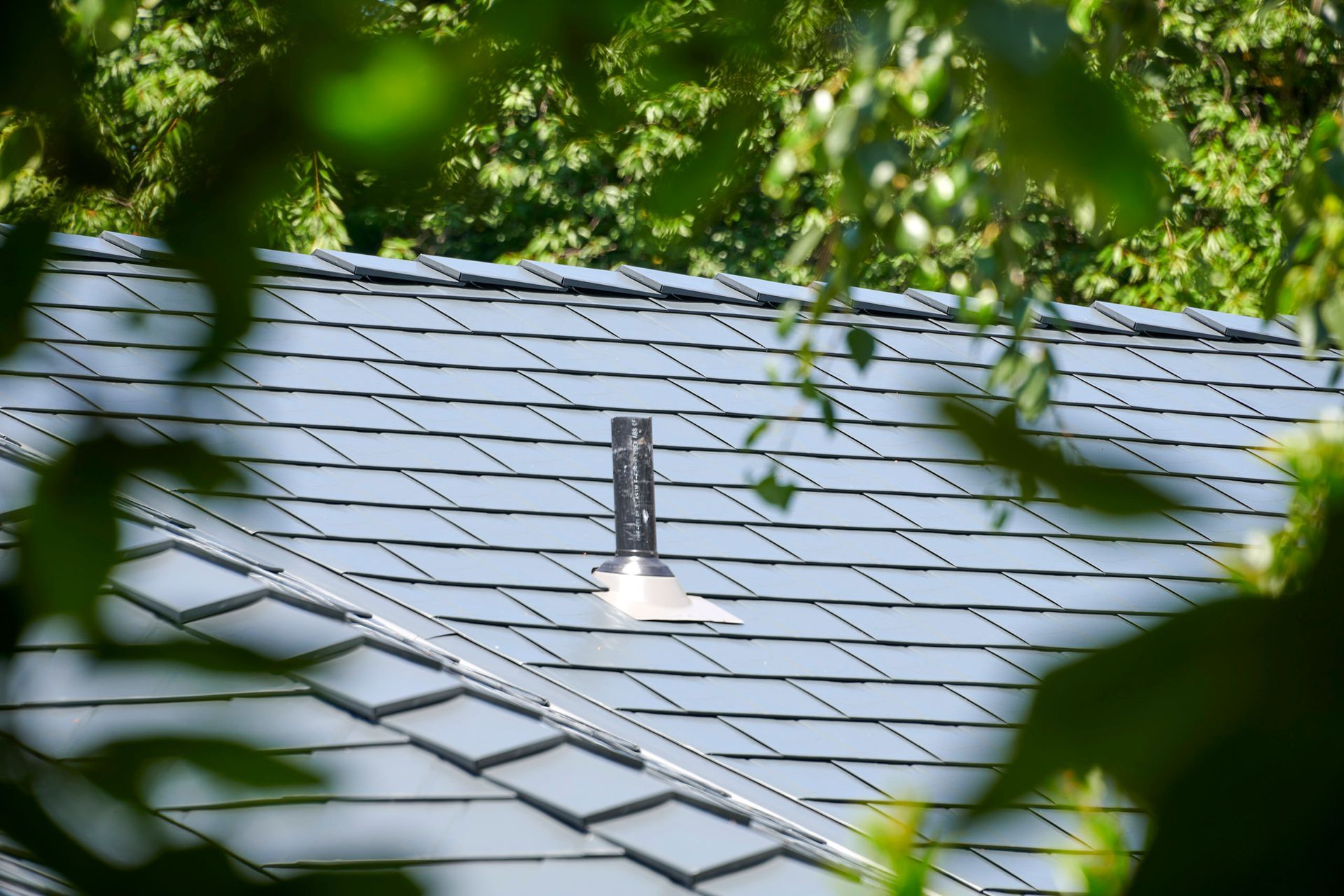 Side view of a triple garage with a Deep Charcoal Interlock Slate aluminum roof installed by Interlock Metal Roofing. The dark roofline contrasts with modern frosted glass garage doors and smooth stucco siding, achieving a contemporary, Northwest architectural style.