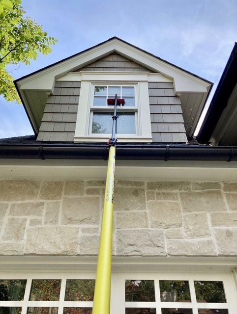 A yellow pole is attached to the roof of a house.