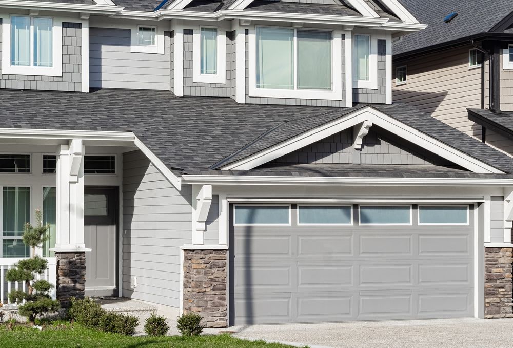A large house with a gray garage door and a gray roof.