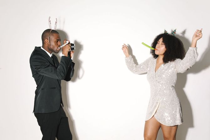 Two people dancing and posing with microphones against a white wall.