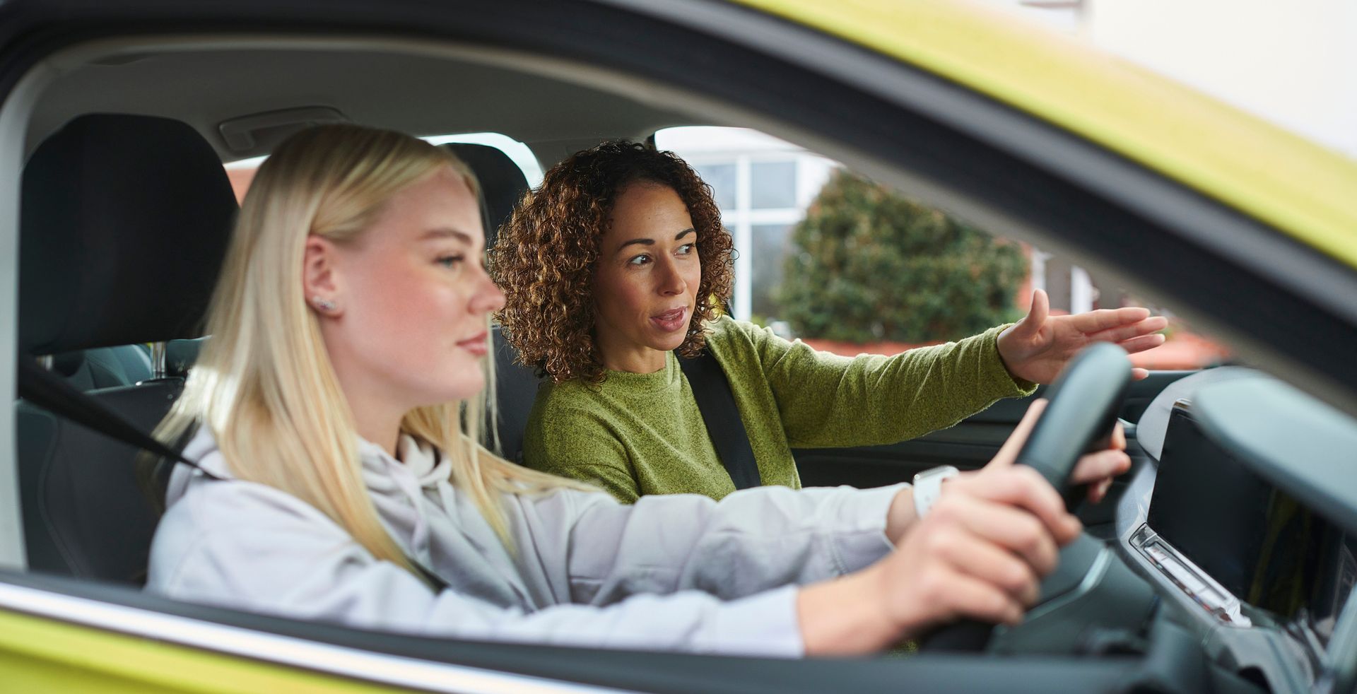 A woman is teaching another woman how to drive a car.