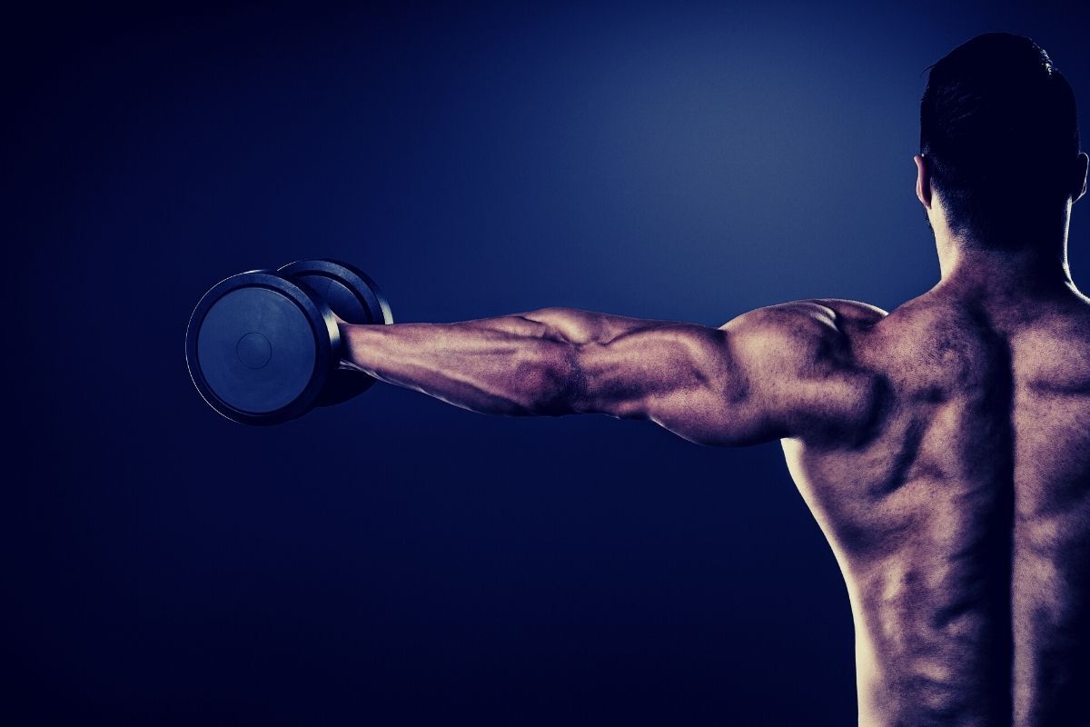 Um homem está levantando um haltere sobre a cabeça.