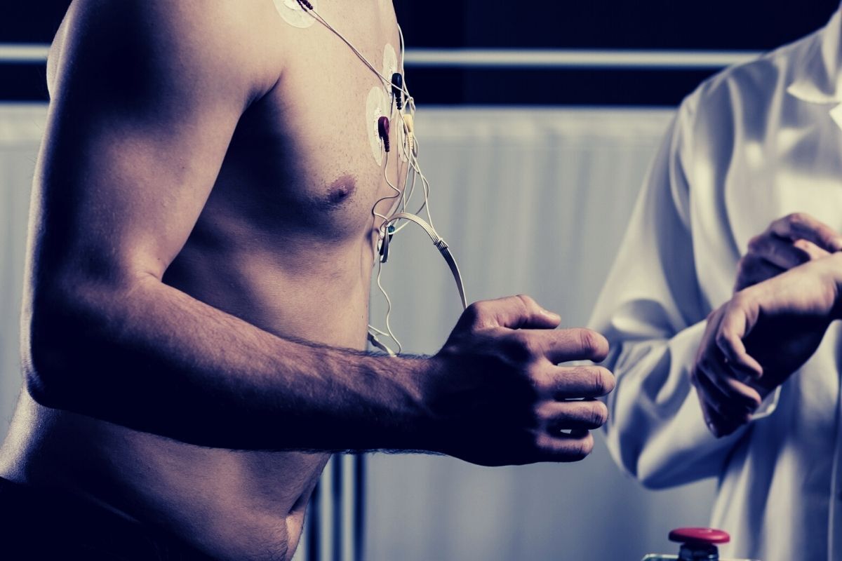 Um homem sem camisa está sendo examinado por um médico