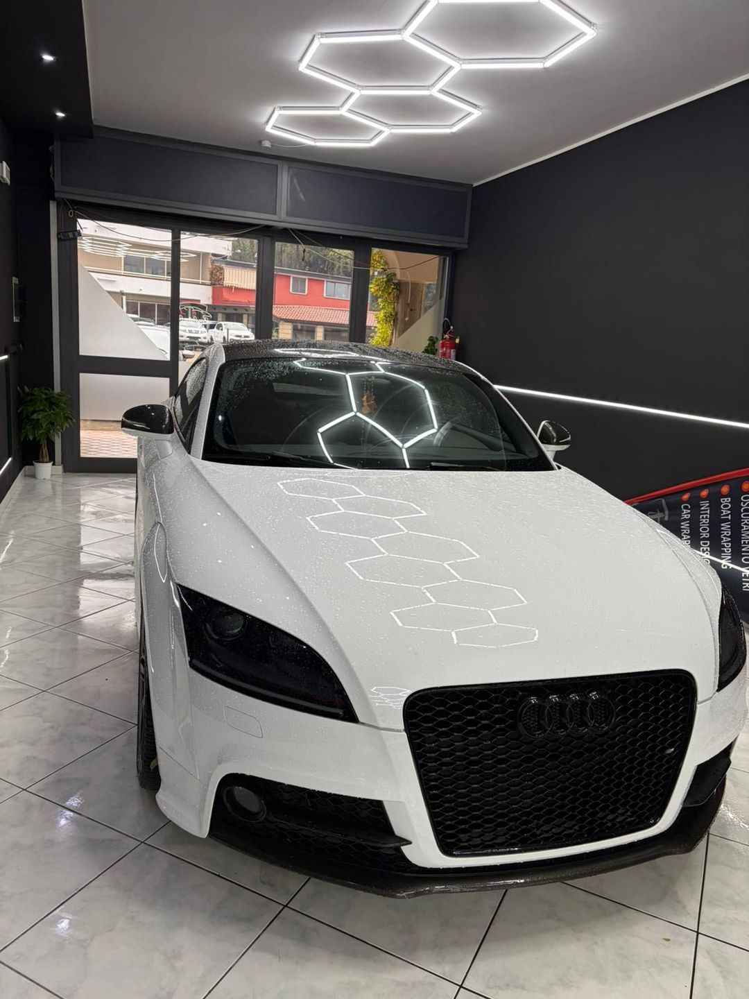 Berlina BMW M3 grigia con cerchi neri e pinze dei freni rosse parcheggiata su una strada.