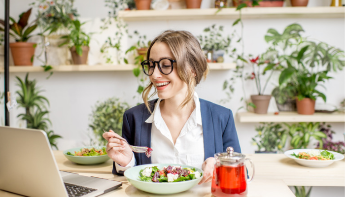 Vibrant business woman reading her PC and having a salad