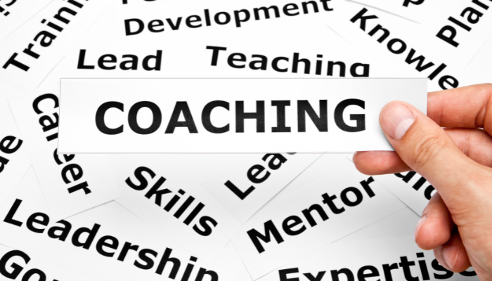 person selecting the word coaching from a pile of related words