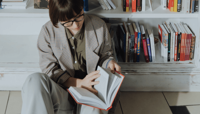 Woman reading hardcover classics in a home library