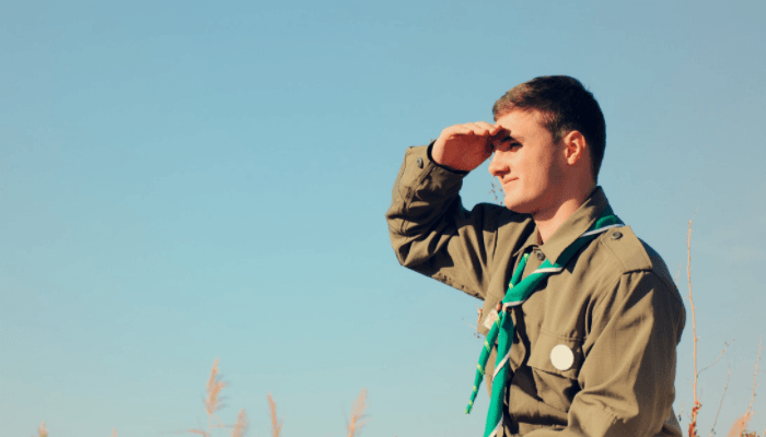 picture of an adult male dressed in a scout uniform searching into the horizon.