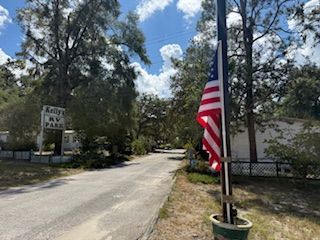 Entrance to Kelly's RV Park, with an American flag on the right. A paved road leads into the park.