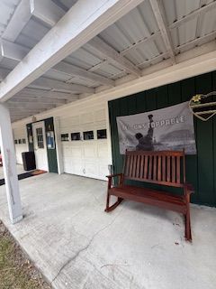 A covered porch with a wooden bench, garage doors, and a banner with a statue image.