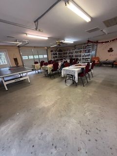 Garage with tables set up, a ping pong table, and shelves in the background.