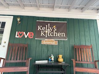Exterior view of Kelly's Kitchen with rocking chairs, a sign, and the word 
