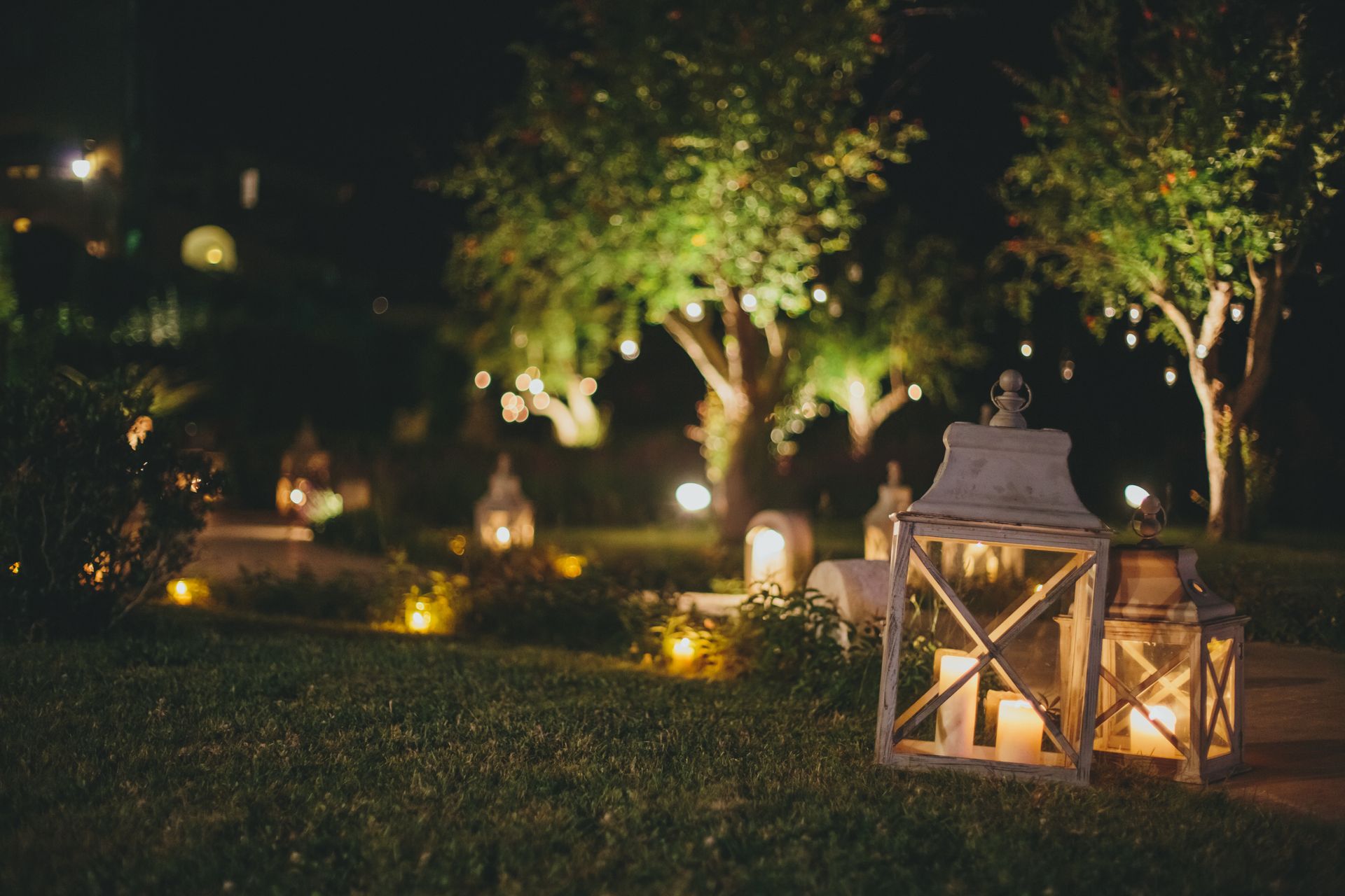 Lantern-lit garden path at night with glowing candles and trees