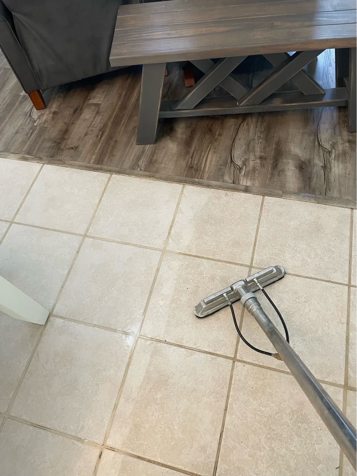 A vacuum cleaner is sitting on a tiled floor in a living room.
