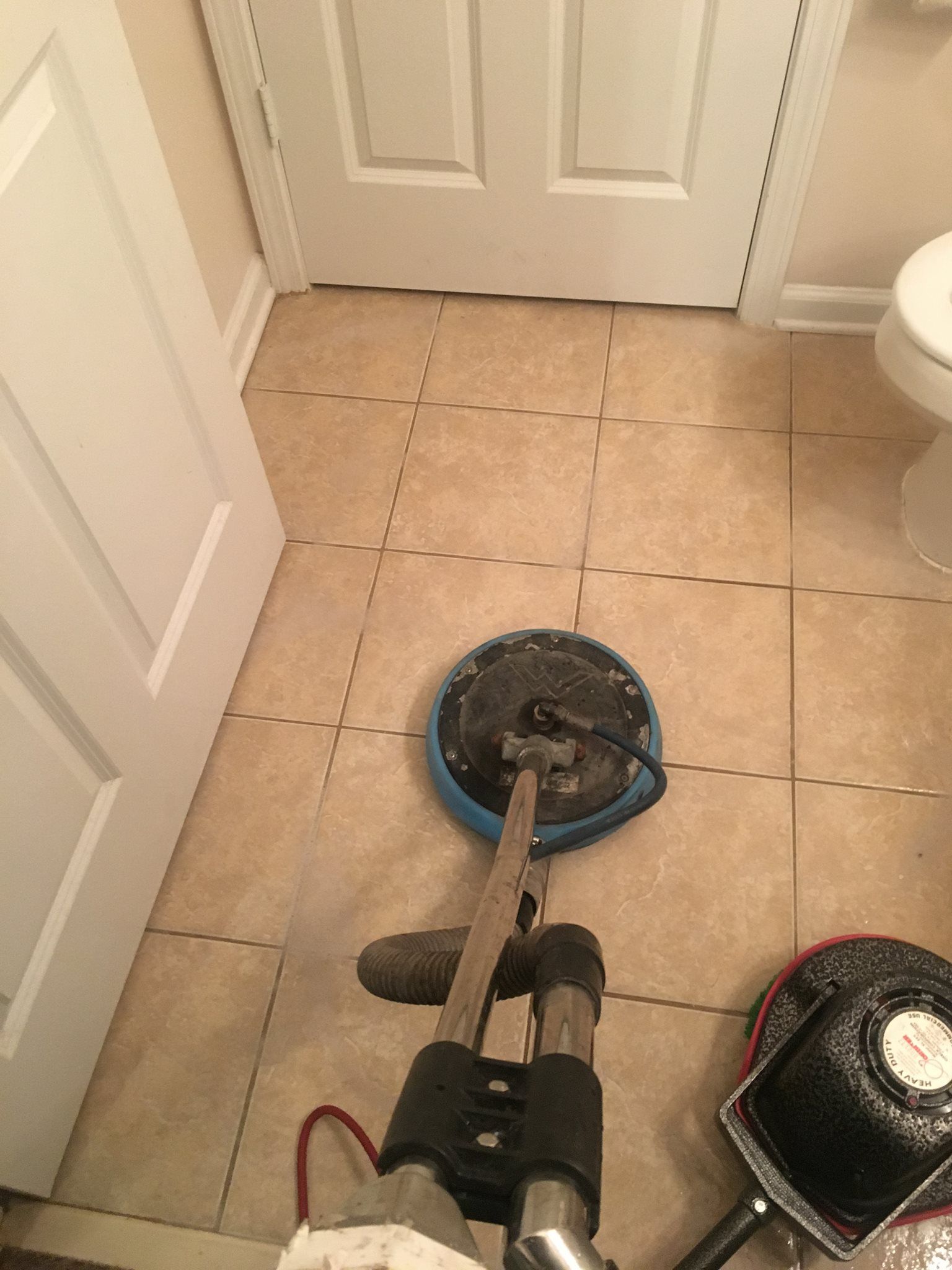 A vacuum cleaner is sitting on a tiled floor in a bathroom next to a toilet.