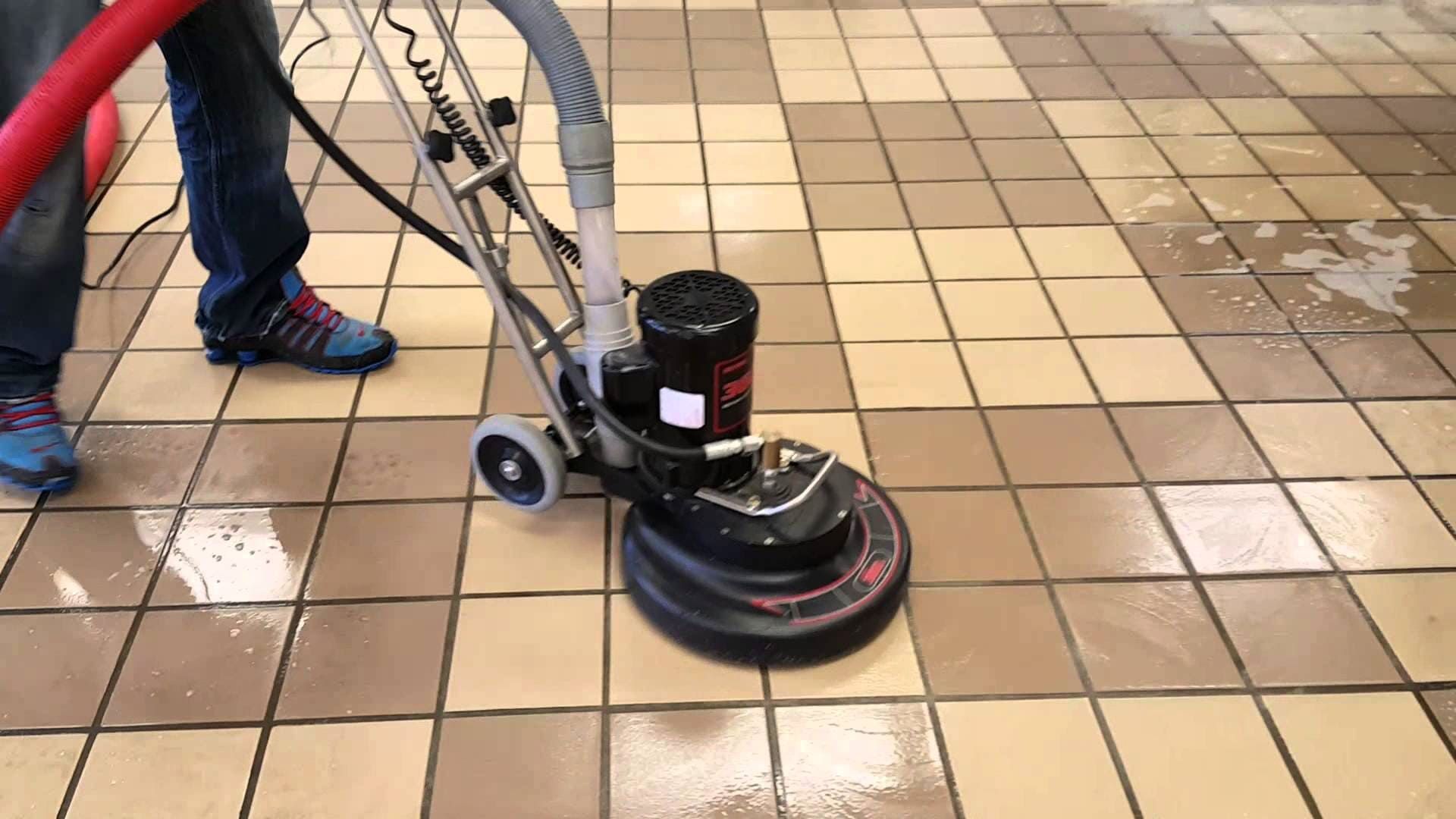 A person is using a machine to clean a tiled floor
