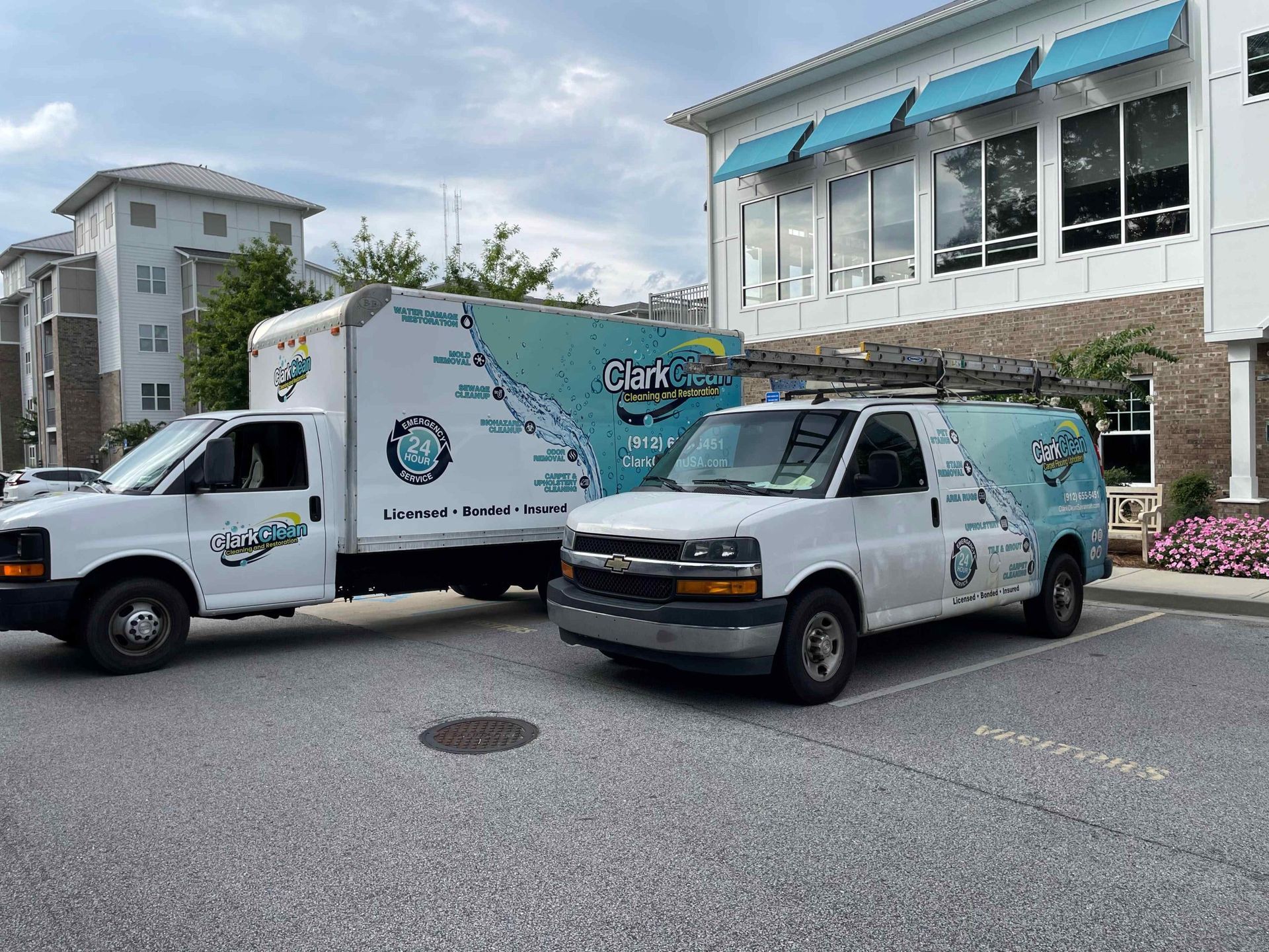 Two vans are parked in front of a building.