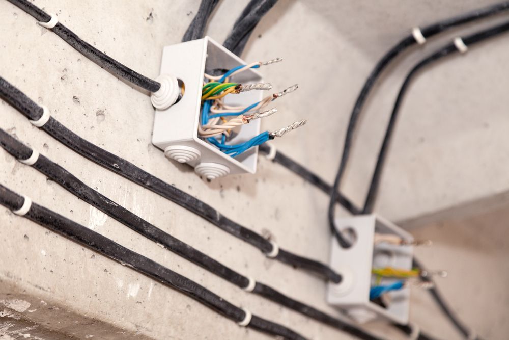 Electrical Wiring in Open White Boxes on a Concrete Wall — Do Right Electrical in Redlynch, QLD