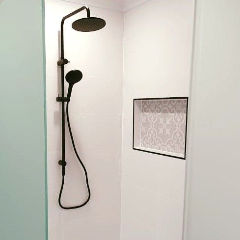 A shower with a black shower head and hose in a bathroom.