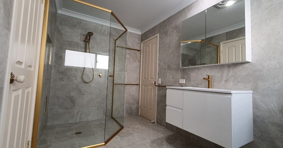 A bathroom with a walk in shower, sink and mirror.