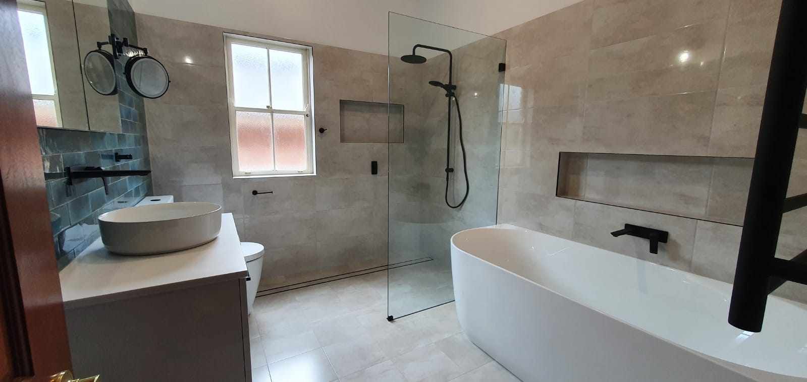 A bathroom with a bathtub, sink, shower and window.