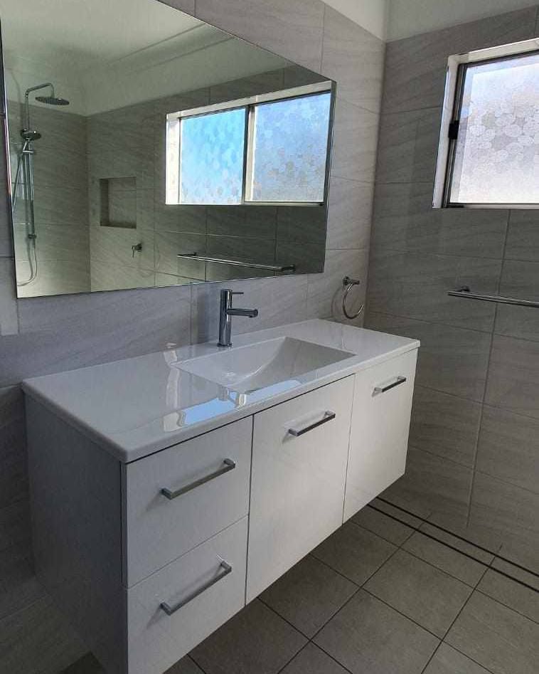 A bathroom with a sink, mirror and shower.