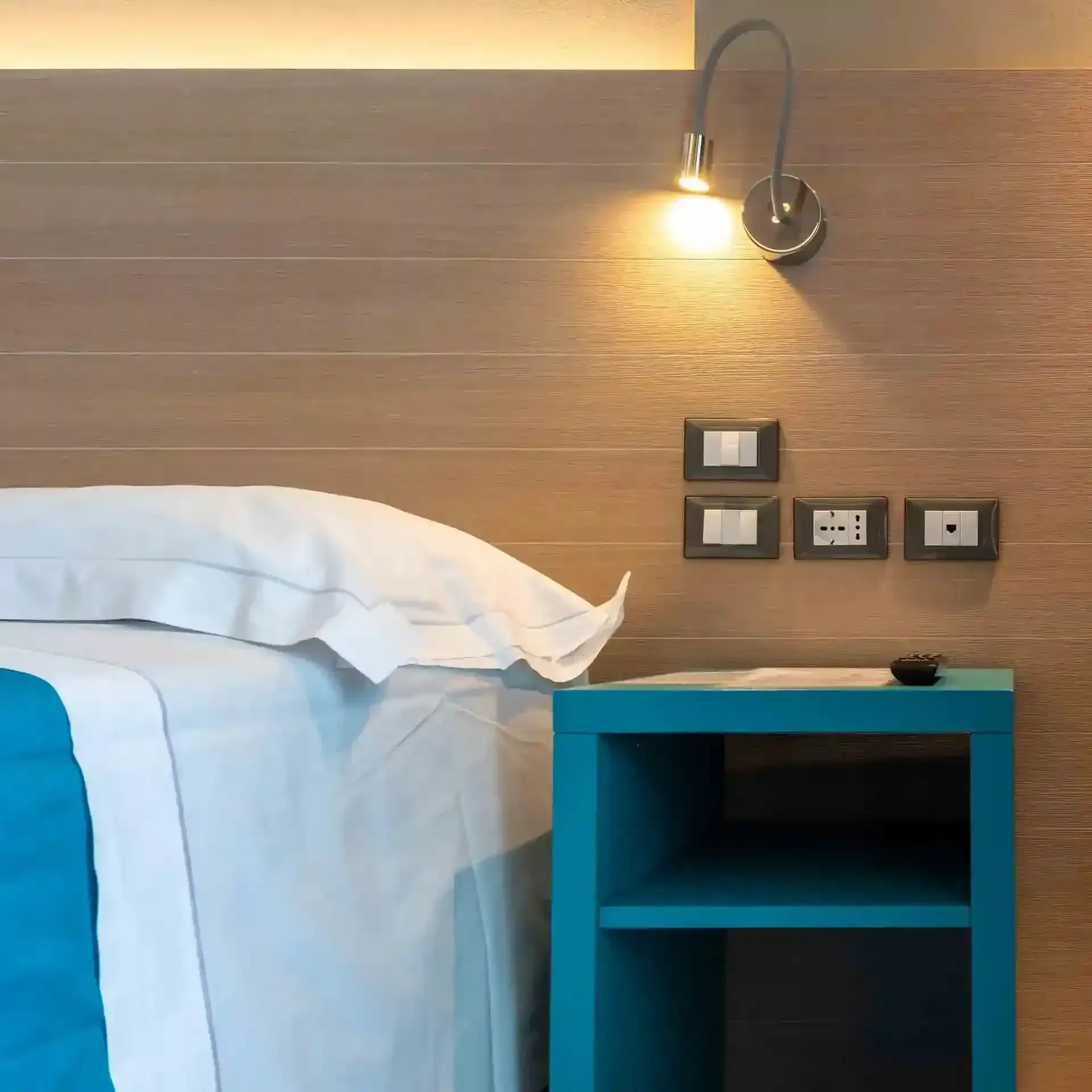 Un letto con un comodino blu accanto