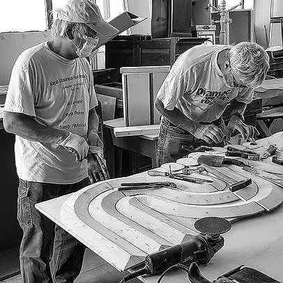 Due uomini stanno lavorando su un pezzo di legno in una fabbrica.