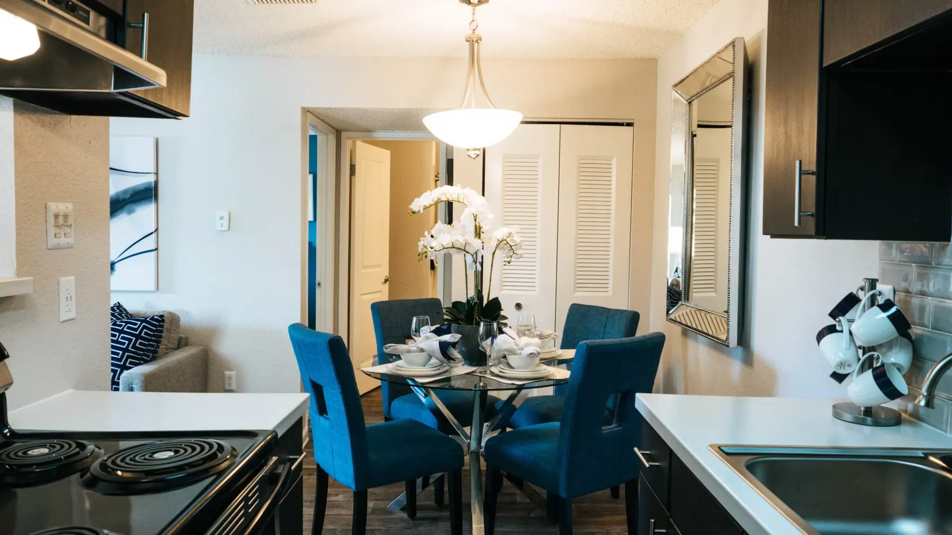 Dining room: Blue chairs surround a table set for dining. Kitchen counter in foreground at Westward Heights in Denver, CO.