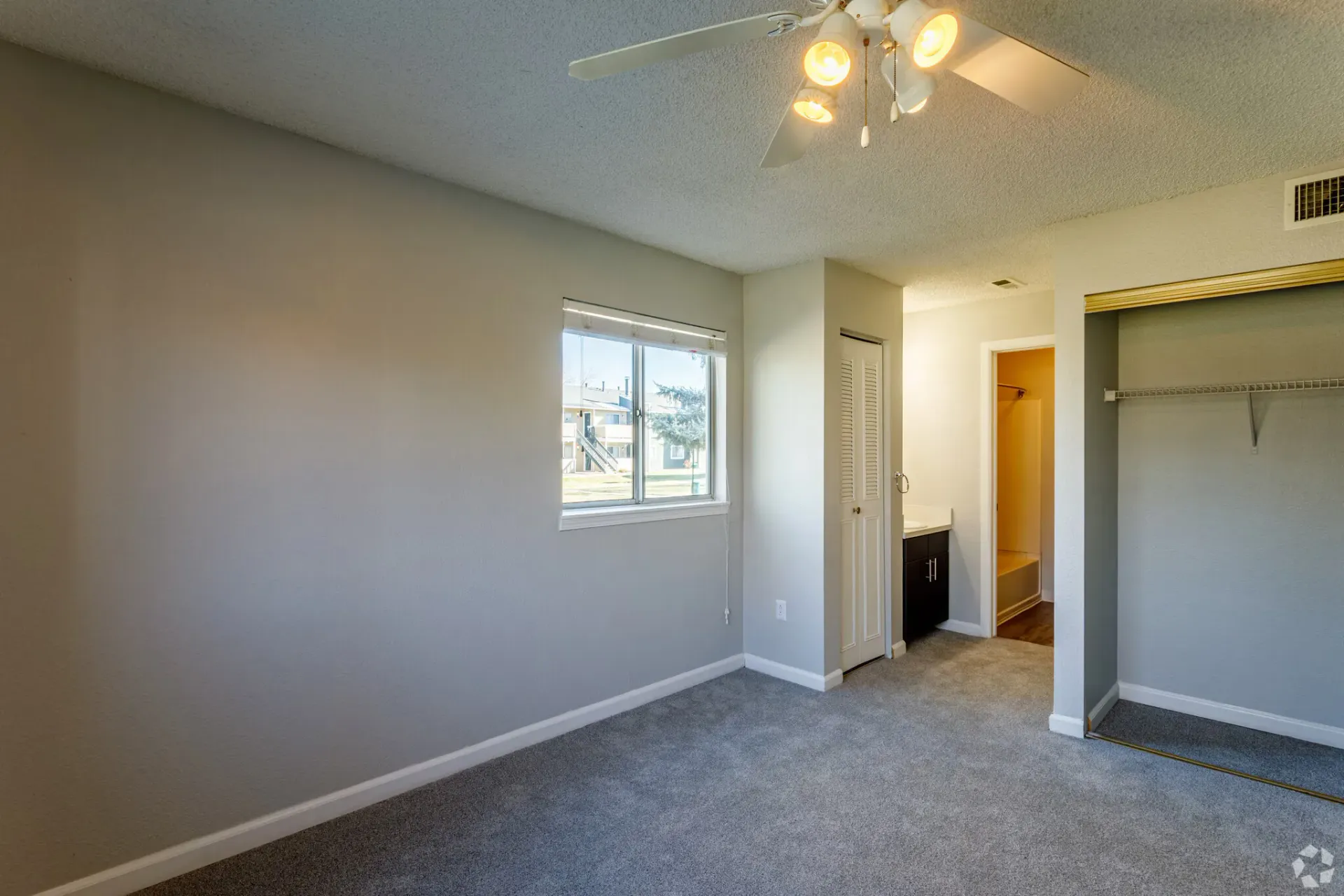 Bedroom with light gray walls, carpet, and a white ceiling fan. A window lets in light at Westward Heights in Denver, CO.