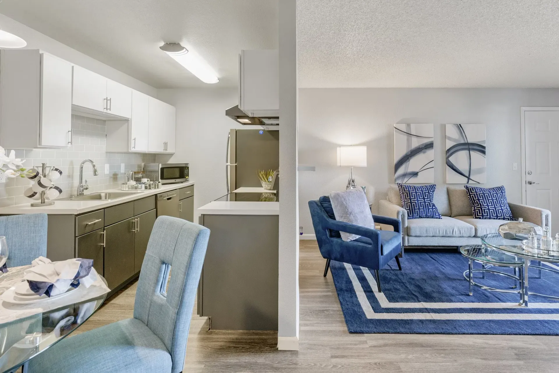 Modern apartment interior with kitchen and living room, in blue, grey, and white tones at Westward Heights in Denver, CO.