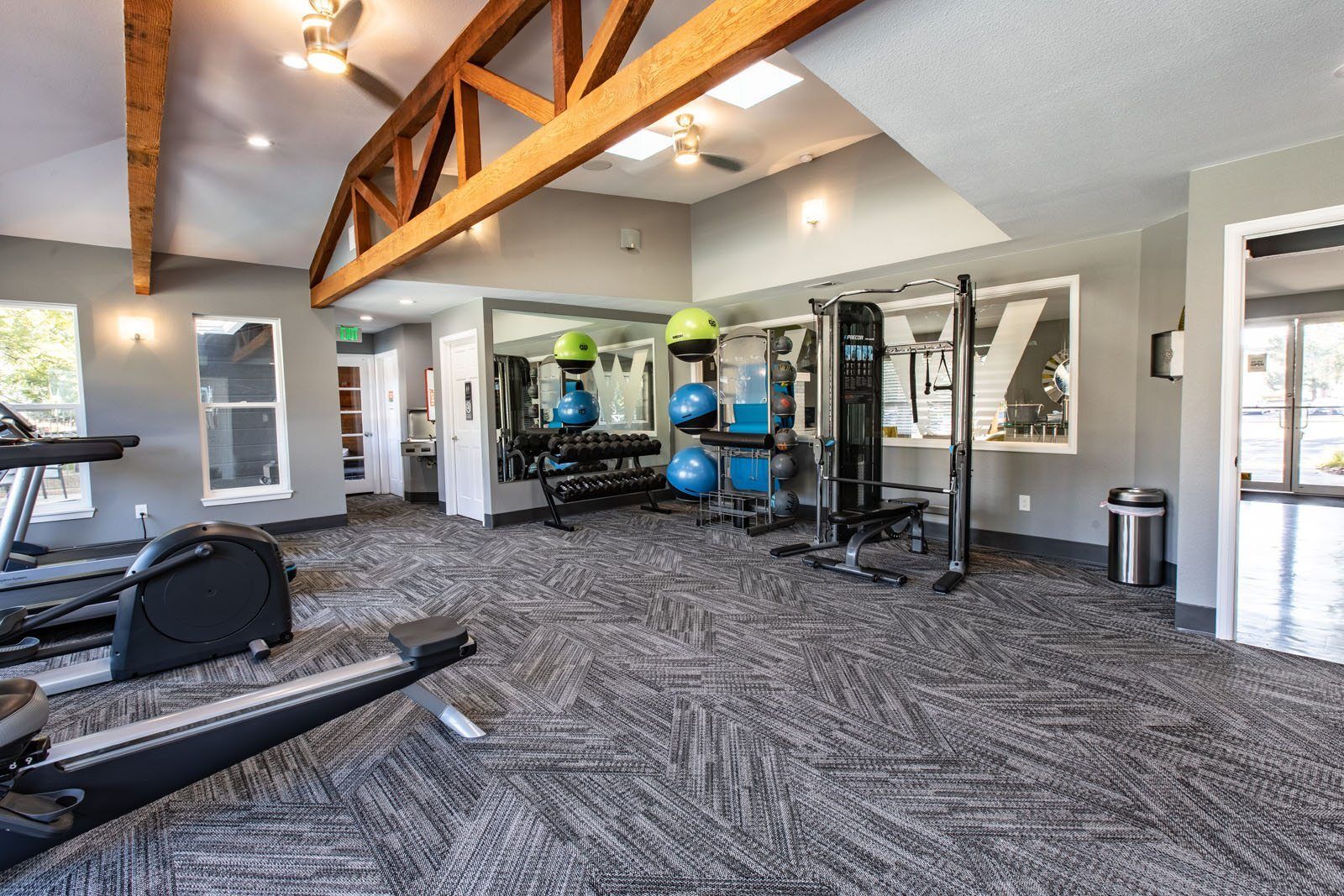 Gym with exercise equipment, including treadmills, weight machines, and rowing machine; gray and wood tones at Westward Heights in Denver, CO.