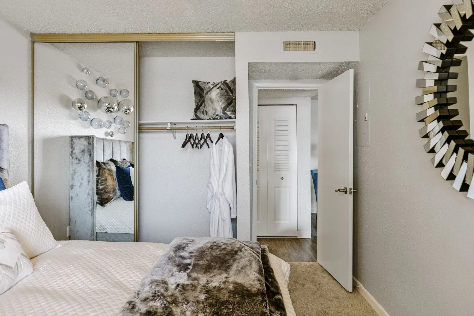Bedroom with bed, closet, mirror, and doorway leading to another room at Westward Heights in Denver, CO.