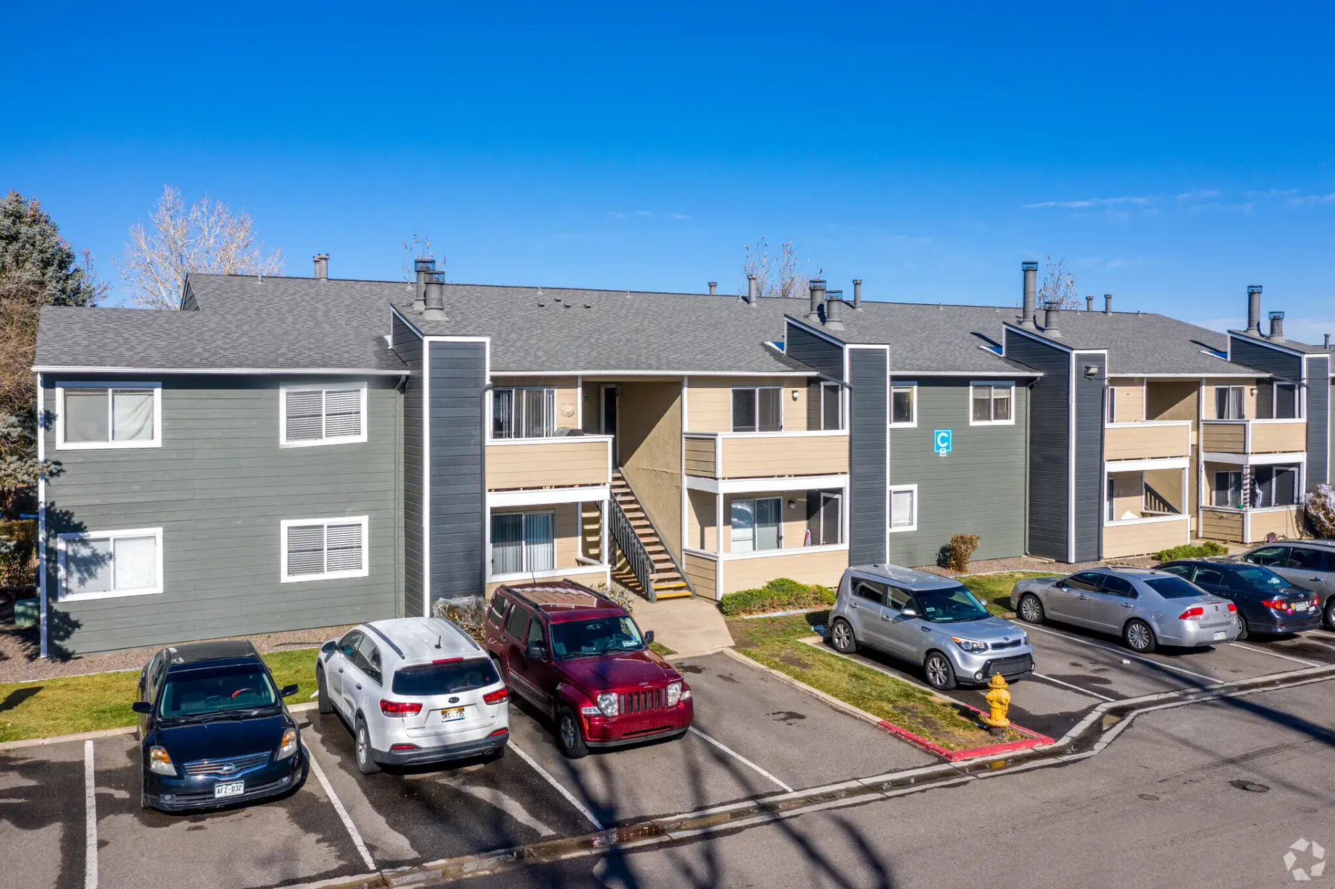 Apartment building with cars parked out front on a sunny day at Westward Heights in Denver, CO.