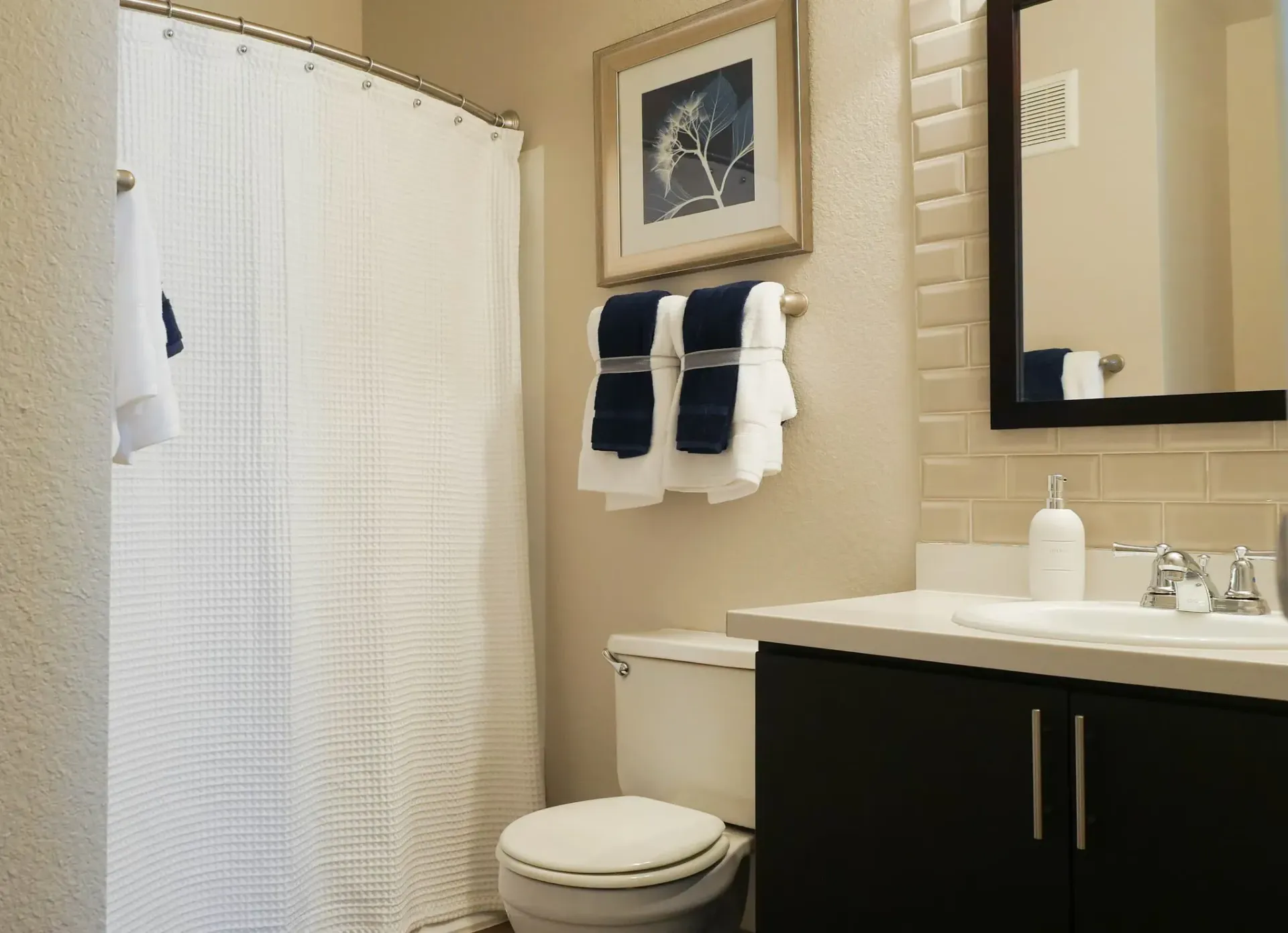 Bathroom with white shower curtain, toilet, vanity, and towels at Westward Heights in Denver, CO.