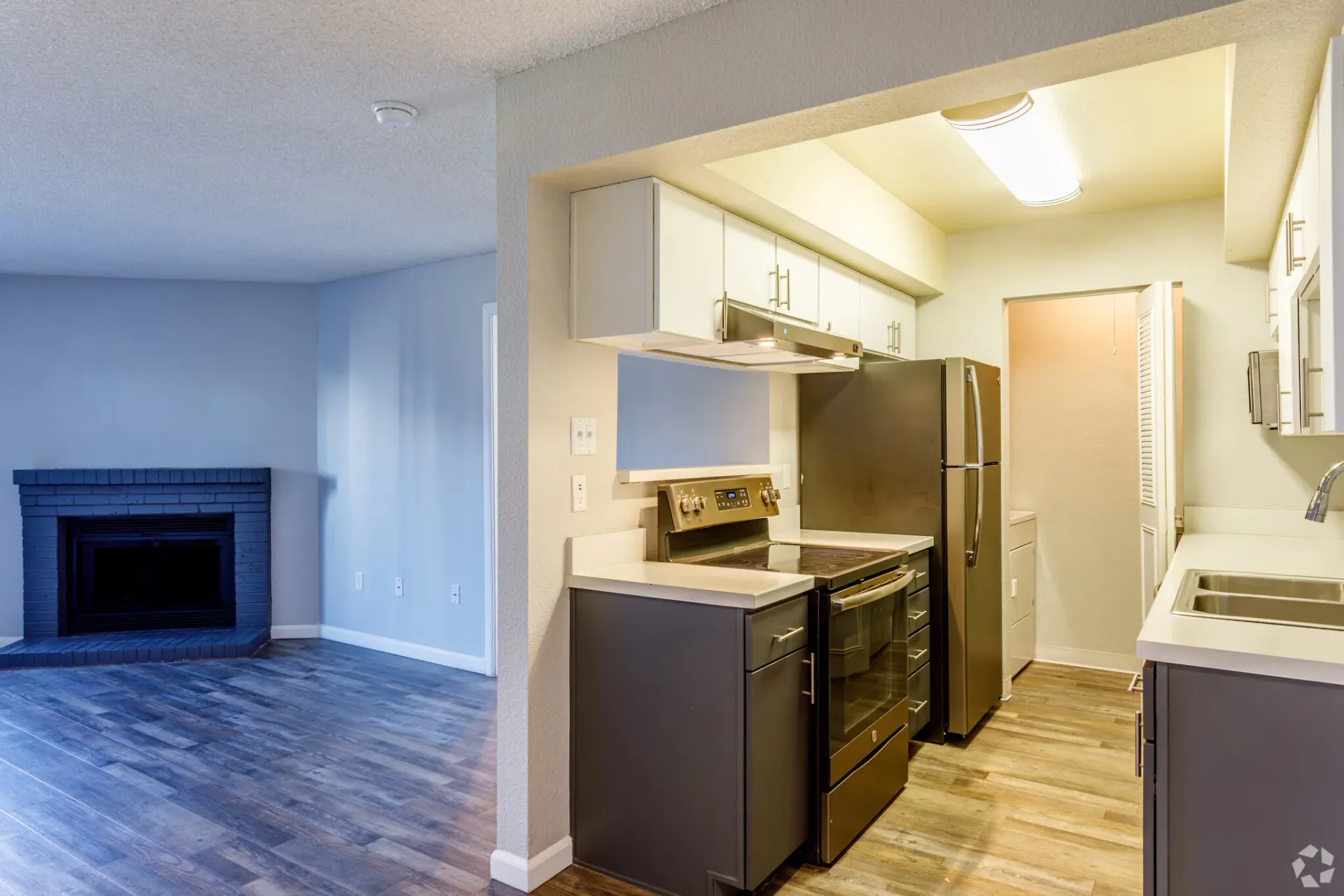 Kitchen with gray cabinets and appliances, open to a living room with a fireplace at Westward Heights in Denver, CO.