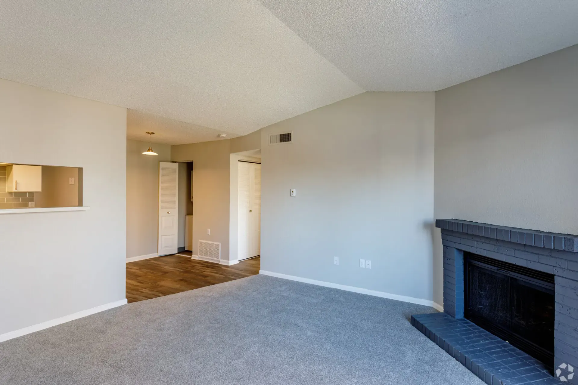 Empty living room with fireplace and gray carpet at Westward Heights in Denver, CO.