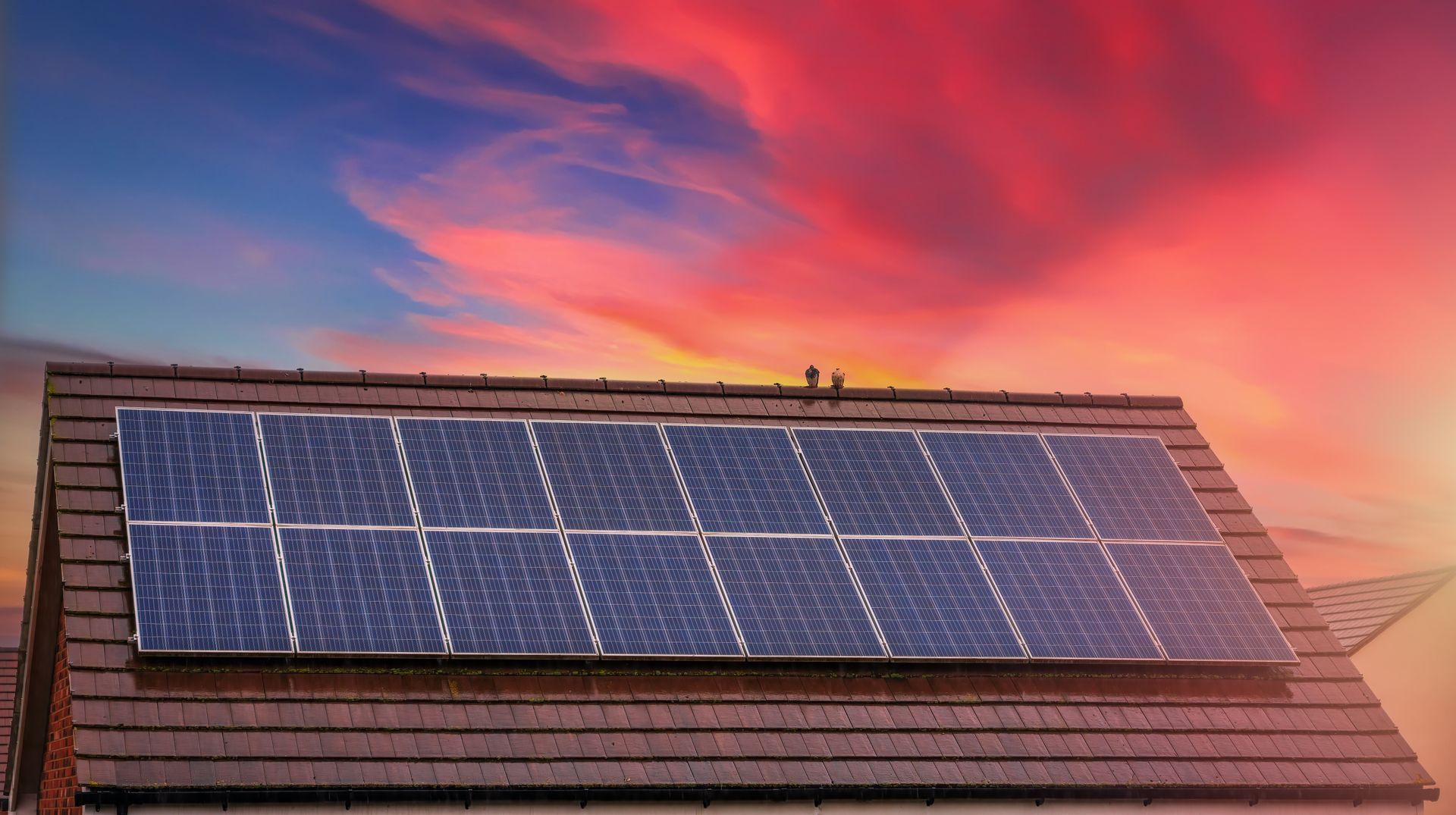 There are many solar panels on the roof of a house.