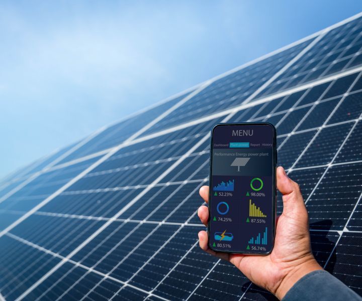 A person is holding a cell phone in front of solar panels