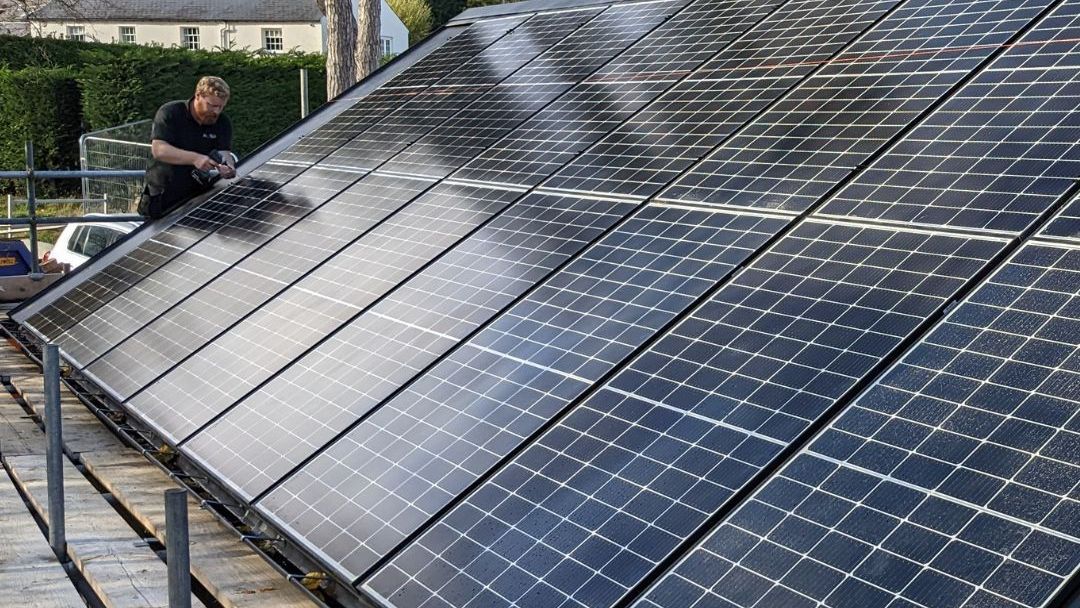 A man is working on a roof with solar panels.