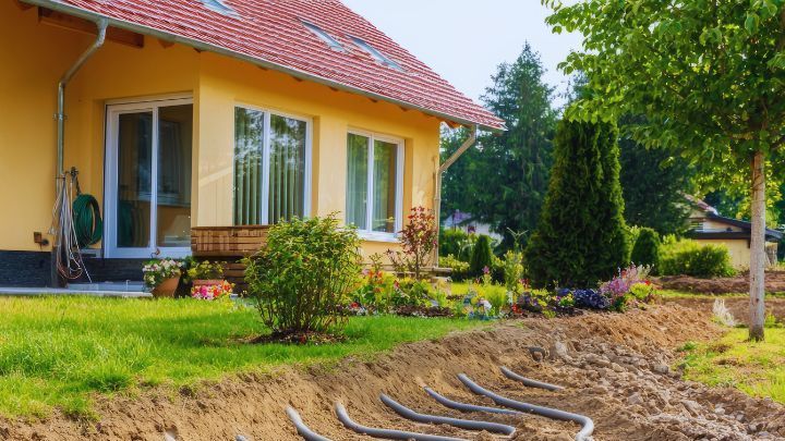 A yellow house with a red roof is being built in a backyard.